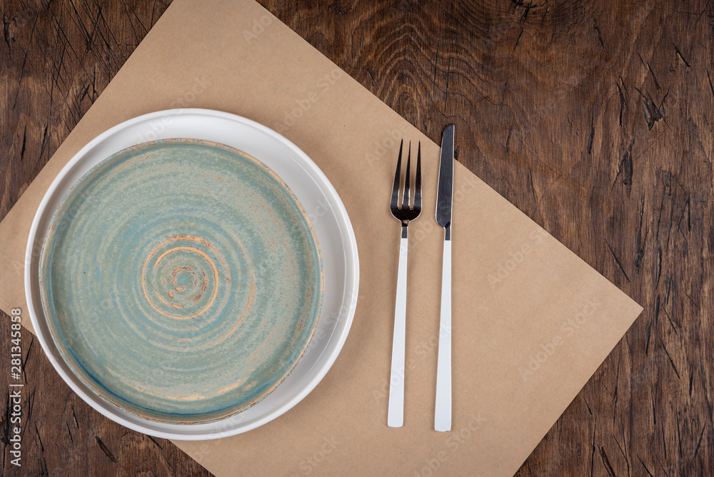 Empty plate with fork and knife on colored wooden background, top view, copy space, mock-up