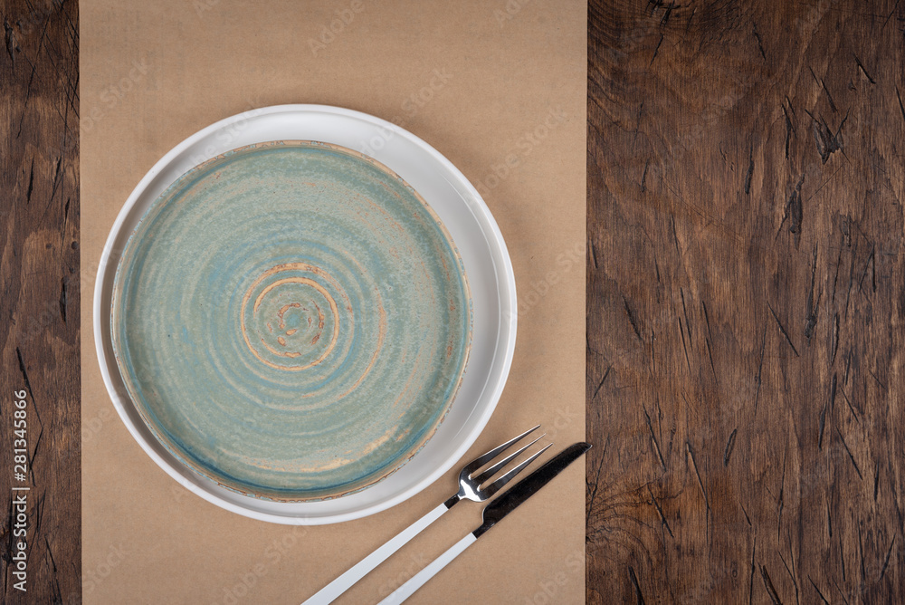 Empty plate with fork and knife on colored wooden background, top view, copy space, mock-up
