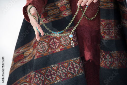 The hands of a woman holding a mala prayer necklace. 