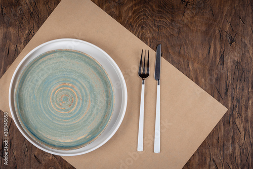 Empty plate with fork and knife on colored wooden background, top view, copy space, mock-up