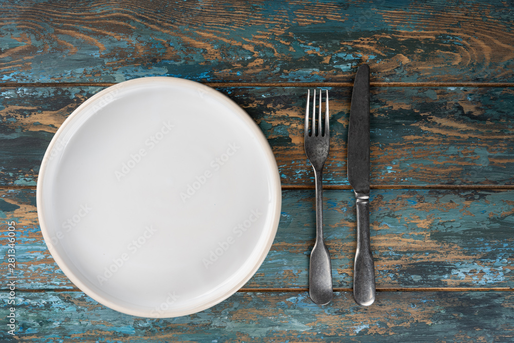 Empty plate with fork and knife on colored wooden background, top view, copy space, mock-up