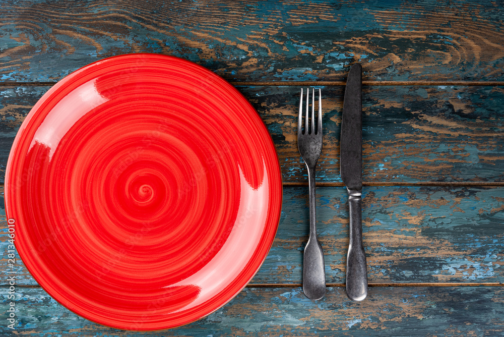 Empty plate with fork and knife on colored wooden background, top view, copy space, mock-up