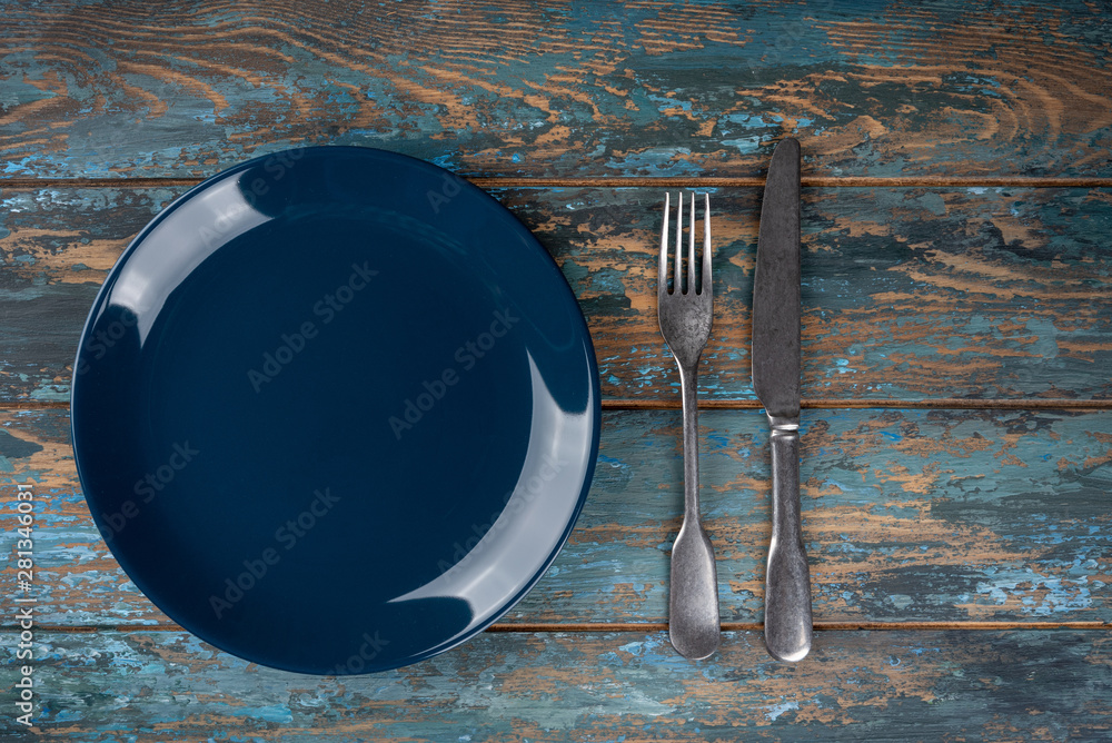 Empty plate with fork and knife on colored wooden background, top view, copy space, mock-up
