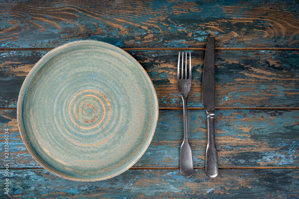 Empty plate with fork and knife on colored wooden background, top view, copy space, mock-up
