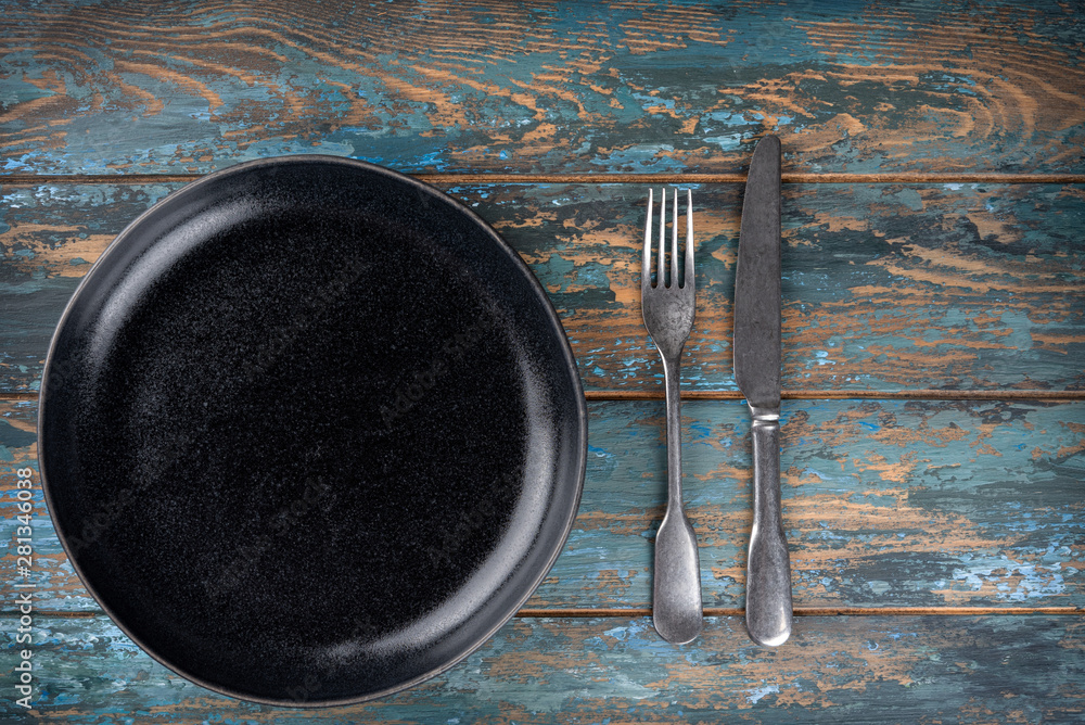 Empty plate with fork and knife on colored wooden background, top view, copy space, mock-up