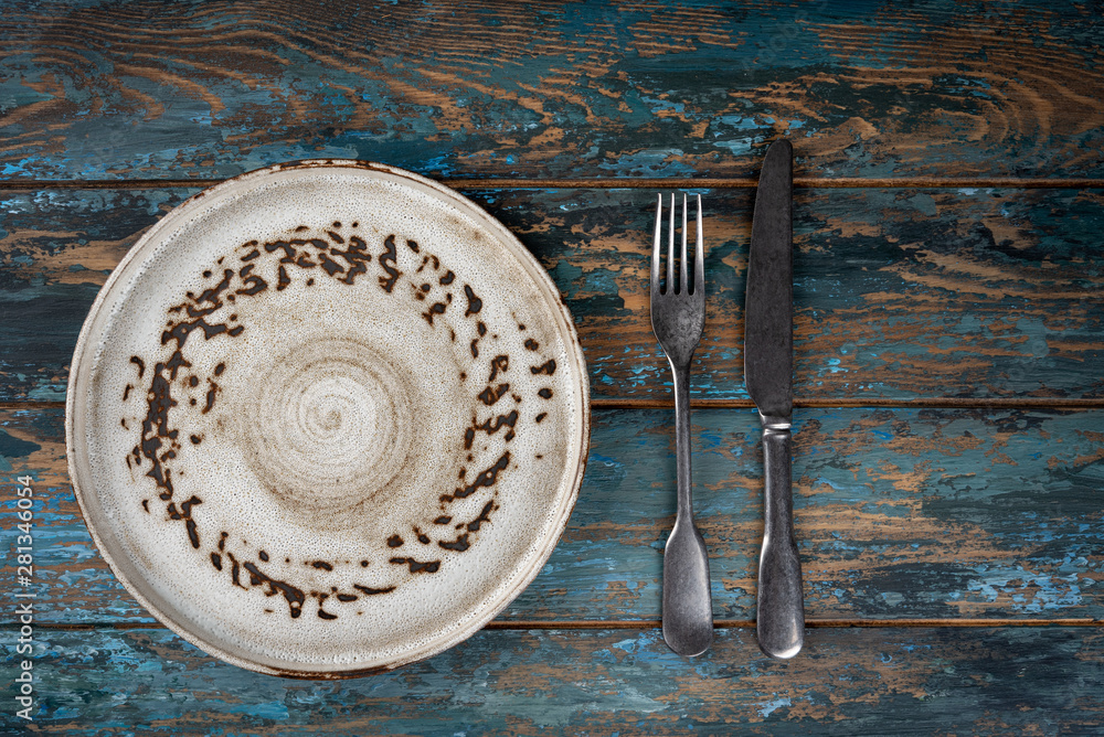Empty plate with fork and knife on colored wooden background, top view, copy space, mock-up