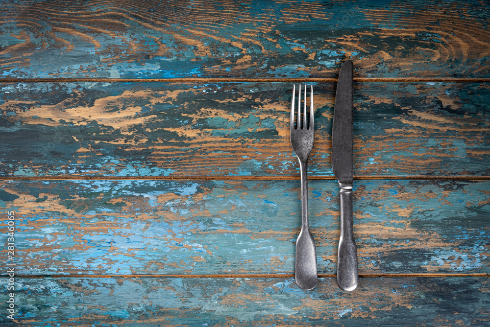 Empty plate with fork and knife on colored wooden background, top view, copy space, mock-up