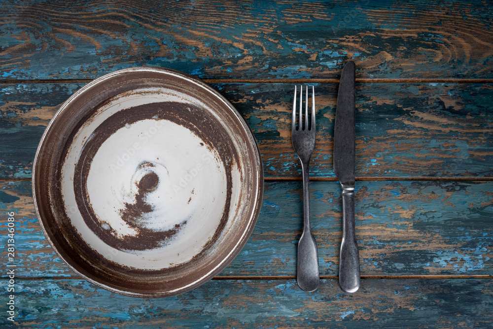 Empty plate with fork and knife on colored wooden background, top view, copy space, mock-up