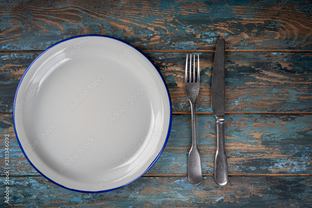Empty plate with fork and knife on colored wooden background, top view, copy space, mock-up