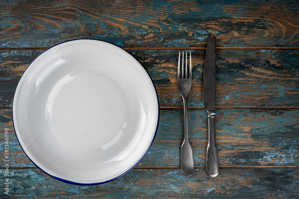 Empty plate with fork and knife on colored wooden background, top view, copy space, mock-up