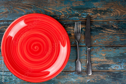 Obraz na płótnie Empty plate with fork and knife on colored wooden background, top view, copy space, mock-up w salonie