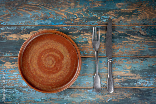 Obraz na płótnie Empty plate with fork and knife on colored wooden background, top view, copy space, mock-up w salonie