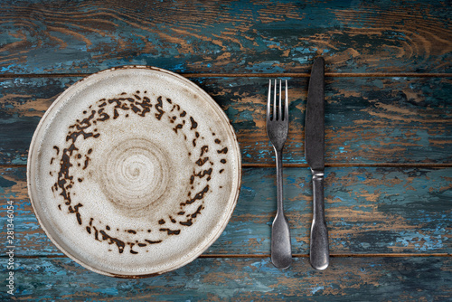 Obraz na płótnie Empty plate with fork and knife on colored wooden background, top view, copy space, mock-up w salonie