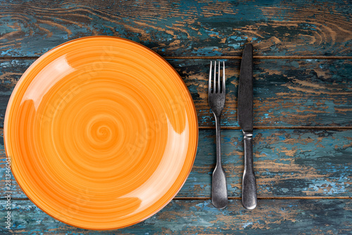 Obraz na płótnie Empty plate with fork and knife on colored wooden background, top view, copy space, mock-up w salonie