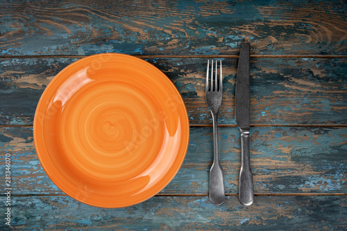Obraz na płótnie Empty plate with fork and knife on colored wooden background, top view, copy space, mock-up w salonie