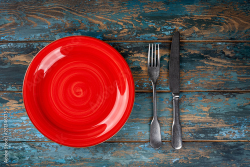 Obraz na płótnie Empty plate with fork and knife on colored wooden background, top view, copy space, mock-up w salonie