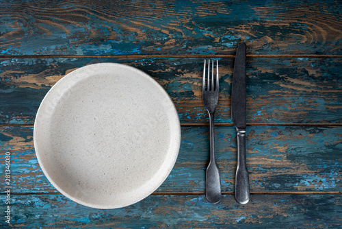 Obraz na płótnie Empty plate with fork and knife on colored wooden background, top view, copy space, mock-up w salonie