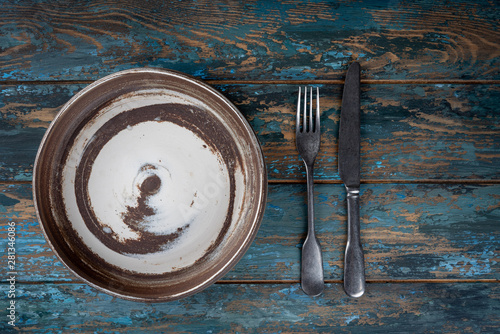 Empty plate with fork and knife on colored wooden background, top view, copy space, mock-up