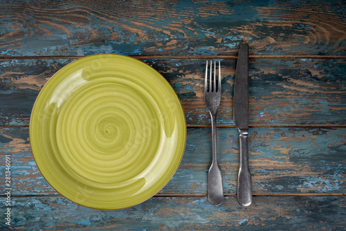 Obraz na płótnie Empty plate with fork and knife on colored wooden background, top view, copy space, mock-up w salonie