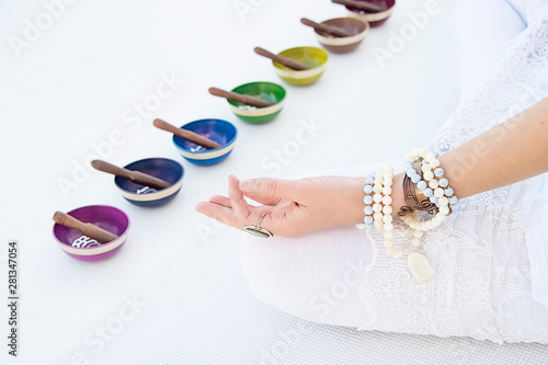 Colorful sound healing singing bowls and a woman's hand in sacred hand gesture. 