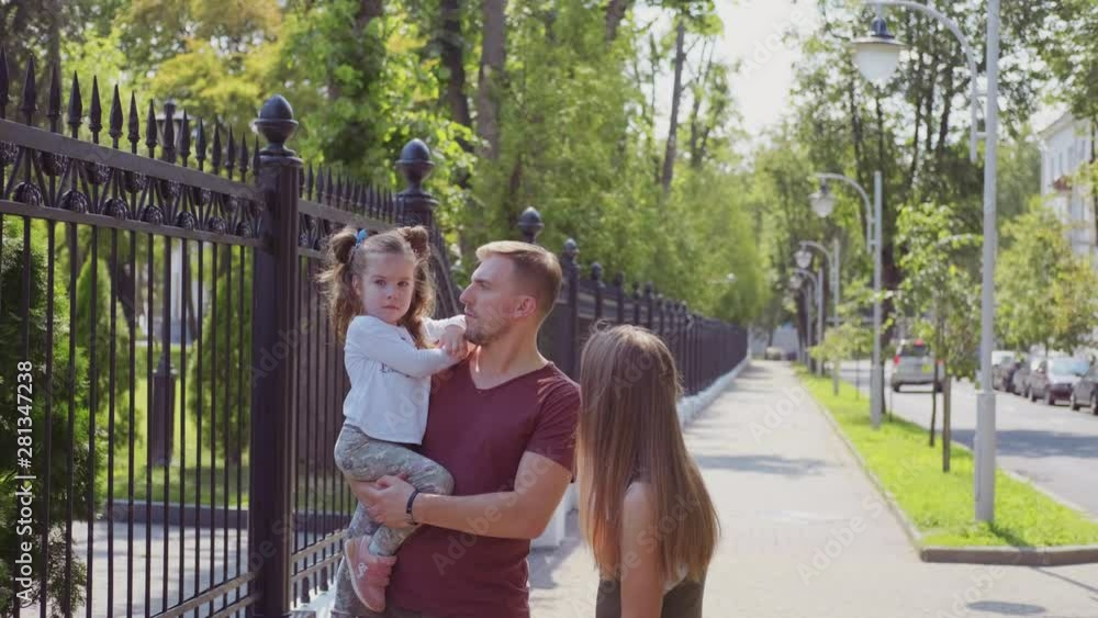 Young family walks down the street on a summer day Young family walks down the street on a summer day