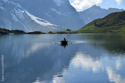 Boat on Trüebsee, Mount Titlis, Switzerland. Calm lake surface wit mountains reflected in the water.