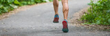 Running shoes panoramic banner of man athlete runner on city road run outdoor panorama of feet and legs calf muscles.