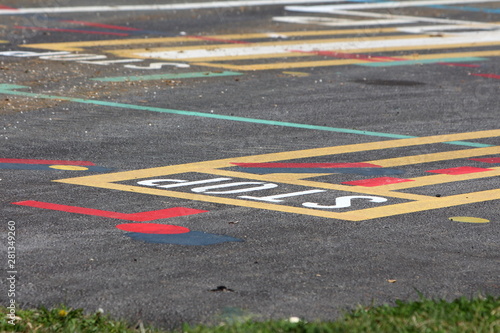 Paved street line testing site with various colorful shapes and letters painted on pavement on warm sunny spring day