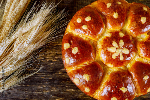 Sheaf of wheat and challah on dark wooden background photo