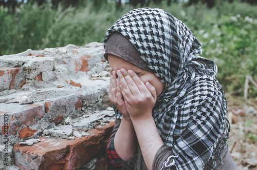 Картината върху платно a refugee child in the war, a Muslim girl with a dirty face on the ruins, the concept of peace and war, the child is crying and waiting for help