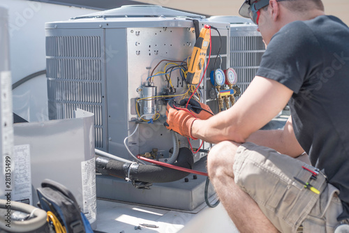 HVAC technician working on controls of air conditioner photo
