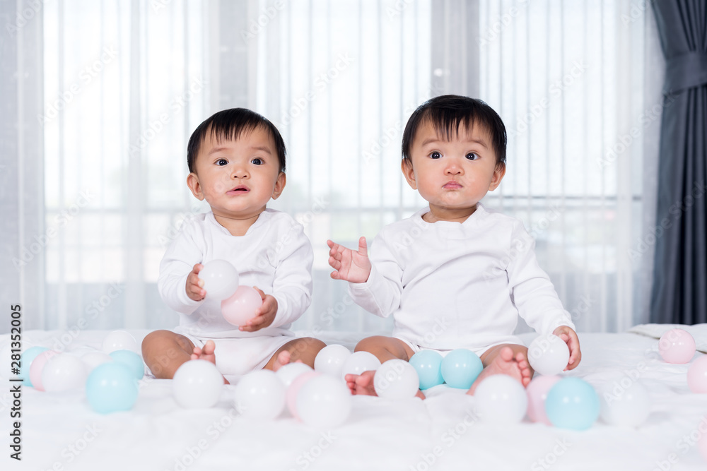 cheerful twin babies playing color ball on bed cheerful twin babies playing color ball on bed