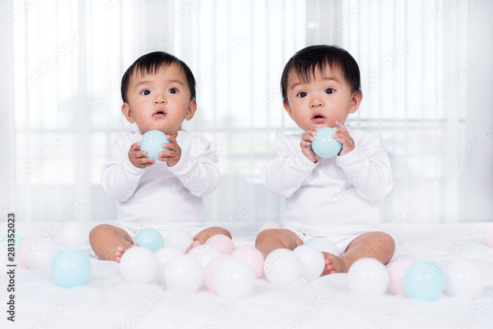 cheerful twin babies playing color ball on bed cheerful twin babies playing color ball on bed