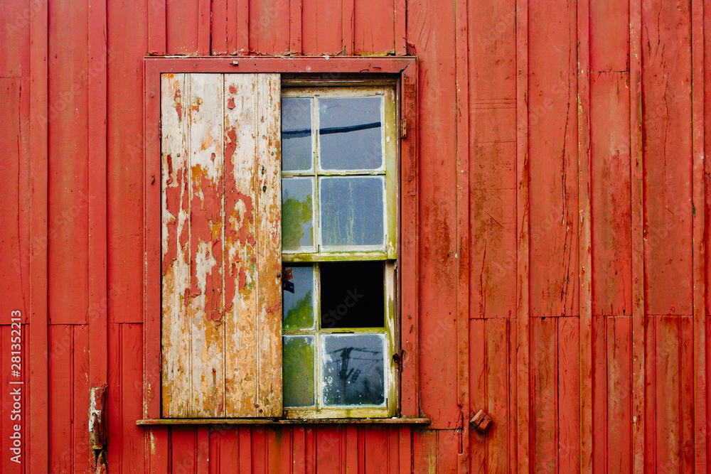 Broken glass and wood window from abandoned house facade with old peeling red wooden wall and grungy surface texture. Broken glass and wood window from abandoned house facade with old peeling red wooden wall and grungy surface texture.
