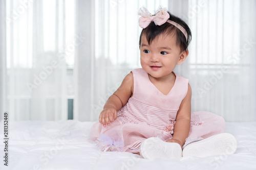 baby in pink dress on bed