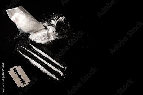 Obraz na płótnie Drug addiction and substance abuse concept theme with lines of cocaine, a small bag with white powder and a blade used to cut each line of narcotics on a dark mirror table with copy space w salonie