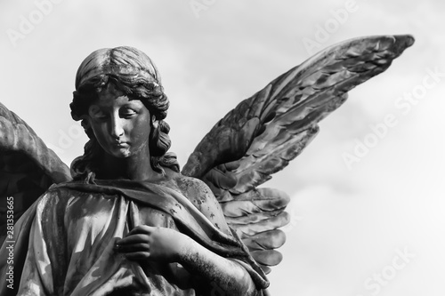 Photos Sad angel sculpture with open long wings across the frame against a bright white sky