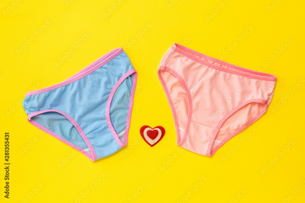 Blue and pink panties with a heart on a yellow background. The concept of meeting lovers. Underwear. The view from the top. Blue and pink panties with a heart on a yellow background. The concept of meeting lovers. Underwear. The view from the top.