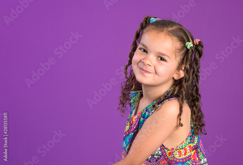 Vászonkép Mixed race little girl with mischievous smile and curly brown hair isolated on p