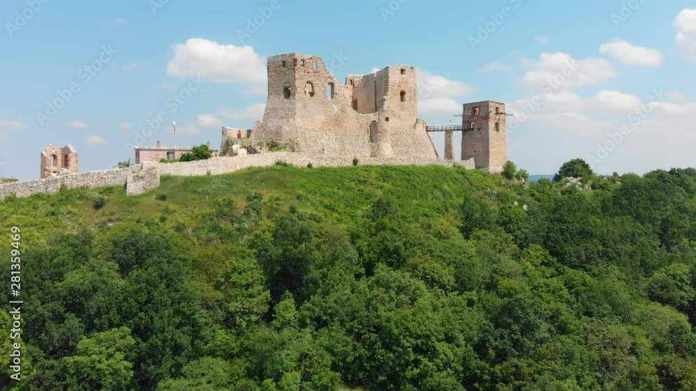 Drone flying toward and over Ruins of Castle atop hill in Hungarian Countryside. Drone shot. View of town. Valley below. Drone flying toward and over Ruins of Castle atop hill in Hungarian Countryside. Drone shot. View of town. Valley below.
