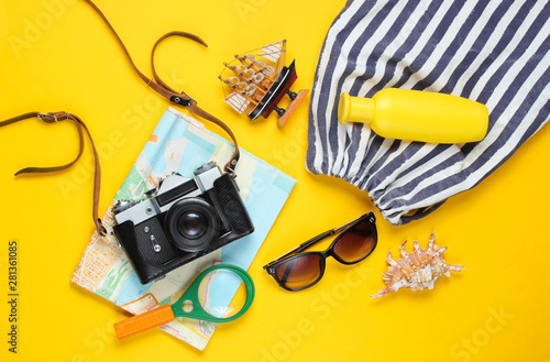 Traveler accessories, retro camera on a yellow background. Trip on the beach, vacation. Summer minimalistic background. Flat lay tourism allegory..Top view