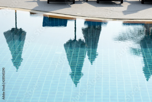 Reflections of palm trees and beach umbrellas in the pool in the morning. Blurred abstract background