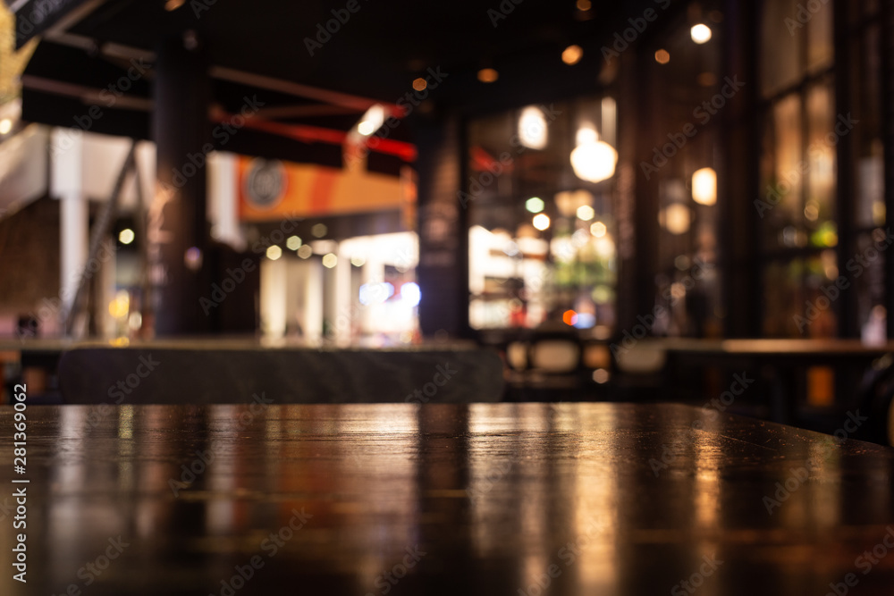 Empty real wood table top with light reflection on scene at restaurant, pub or bar at night.