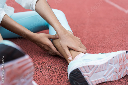 Close up of hand Athletic woman suffering or injury leg after exercise. Asian woman or student has pain in his foot or shin while running track has calf cramp and touching hurt leg or sprained ankle