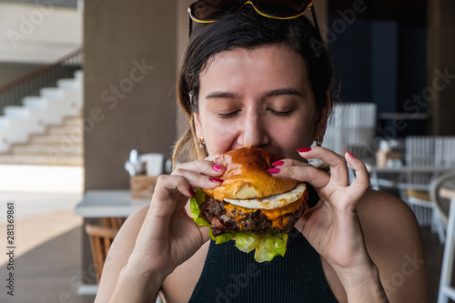 Young girl eats burger  american unhealthy calories meal. Unhealthy eating concept