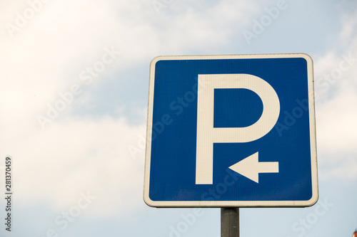Road sign against the sky. White letter P on a blue background. Sign "Parking". Summer day.