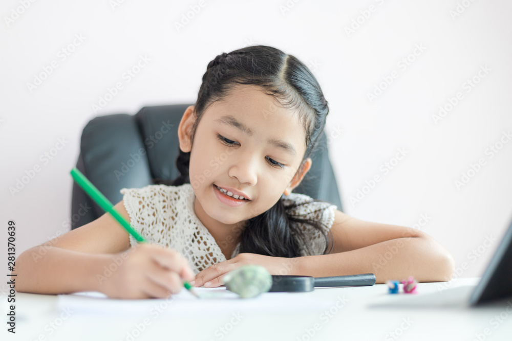 Little Asian girl using the pencil to write on the paper doing homework for education concept select focus shallow depth of field Little Asian girl using the pencil to write on the paper doing homework for education concept select focus shallow depth of field