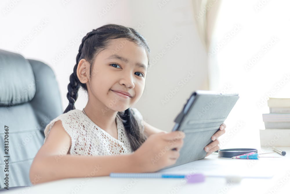 Little Asian girl using tablet and smile with happiness for education concept select focus shallow depth of field