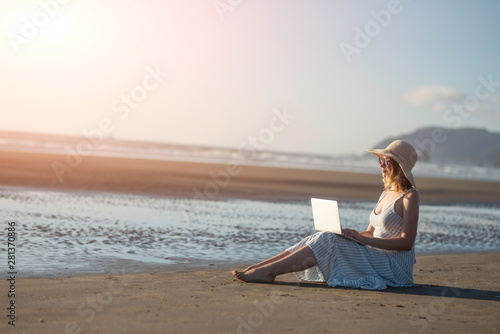 Young girl in sunglasses works on a laptop on the ocean at sunset, freelancing, making money on the Internet, getting money online, lifestyle, Banne, with space