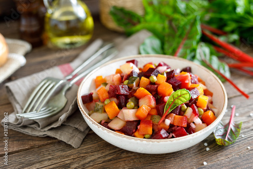 Beetroot or beet salad with boiled vegetables on wooden rustic table closeup